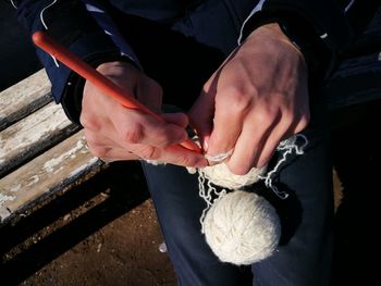 Midsection of woman holding wool balls on bench