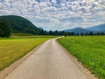 Road amidst field against sky