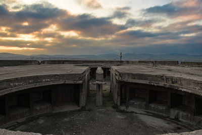 Abandoned built structure against cloudy sky