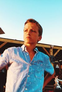 Low angle view of young man looking away against clear sky
