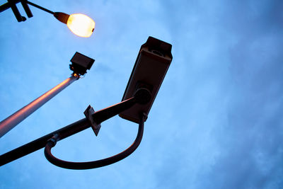 Low angle view of cctv camera and light against sky