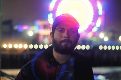 Close-up portrait of young man in illuminated city at night