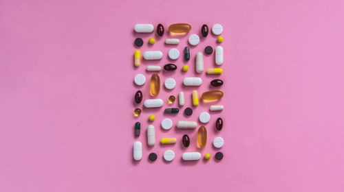 Different types of pills lie on a pink background, medicine treatment, vitamins, antibiotic