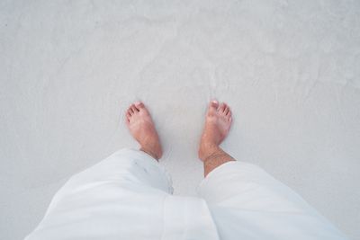 Low section of man standing on sand