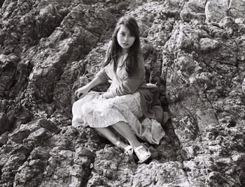 Portrait of woman standing on tree trunk