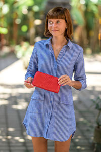 Portrait of young woman standing against blurred background