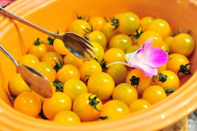 Close-up of yellow cherry tomatoes and flower in bowl