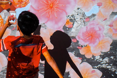 Rear view of people standing by flowering plants