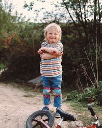 Portrait of crying boy showing injured elbow while standing by bicycle