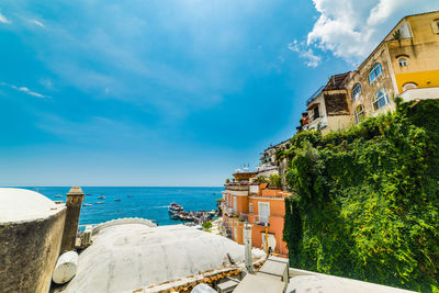 Buildings by sea against blue sky