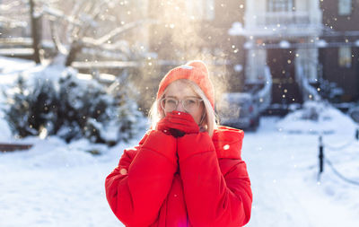 Young stylish blonde woman on the street has fun, posing in snowy, frosty