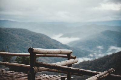 Metallic railing against mountain range against sky