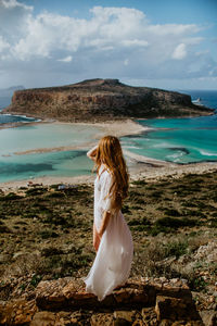 Woman standing at beach against sky