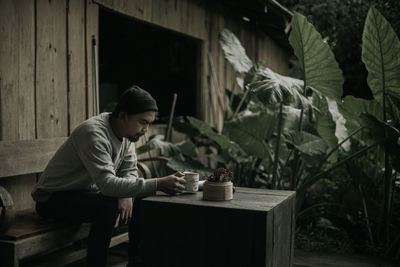 Side view of young man looking through window