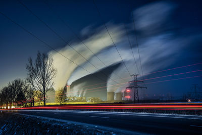 Light trails on road against sky at night