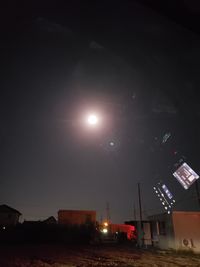 Illuminated street amidst buildings against sky at night