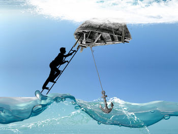 Low angle view of man by sea against blue sky