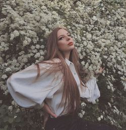 Portrait of young woman standing against tree