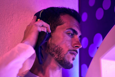 Close-up of a young man listening music at night. color lights