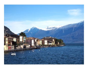 Scenic view of sea by townscape against sky