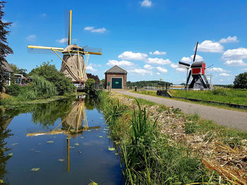 Traditional windmill by canal against sky