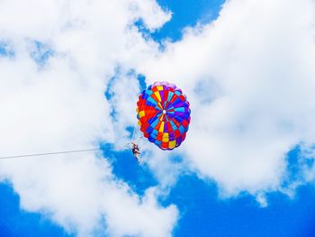 Low angle view of person parasailing against sky