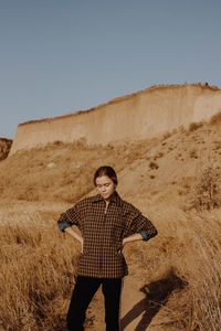 Young woman standing by plants against sky