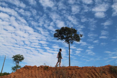 Rear view of woman walking on field against sky