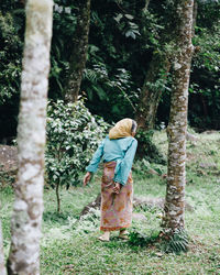 Rear view of woman standing by tree on field