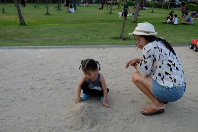 Mother with daughter playing with sand at park