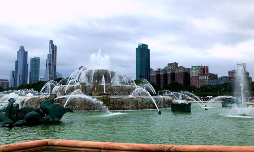 Fountain in city against sky