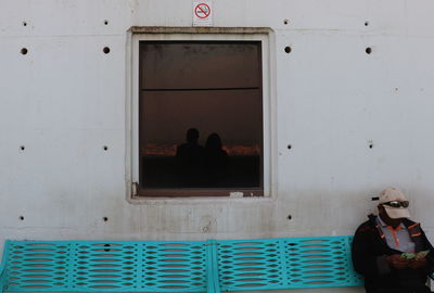 Rear view of people sitting on window