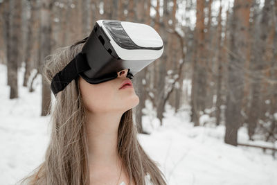 Woman wearing virtual reality simulator against trees outdoors