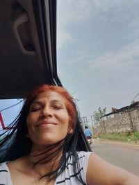 Portrait of smiling young woman against sky