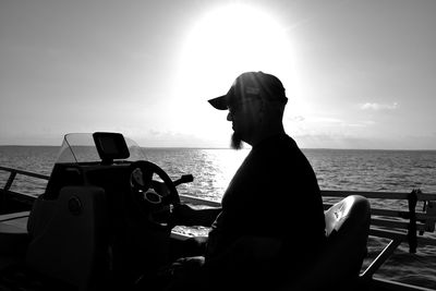 Close-up of man sitting on boat at beach against sky