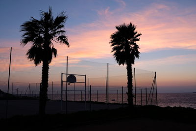 Silhouette palm trees on beach against sky during sunset