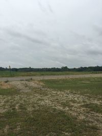 Scenic view of grassy field against cloudy sky