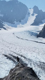 Man standing on snowcapped mountain against sky