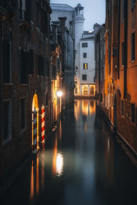 Canal amidst buildings in city at night