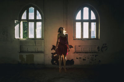 Rear view of woman standing against window in building