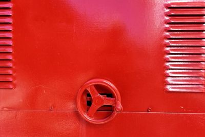 Close-up of red metallic wheel on wall