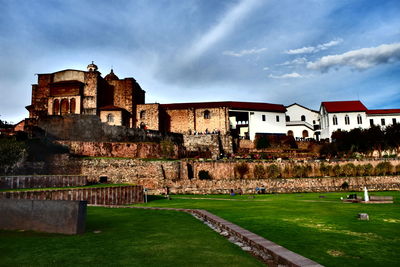 Old building by lawn against sky