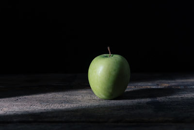 Close-up of apple on table against black background