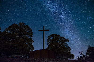 Low angle view of cross on tree against sky at night