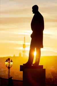 Silhouette man standing against illuminated orange sky