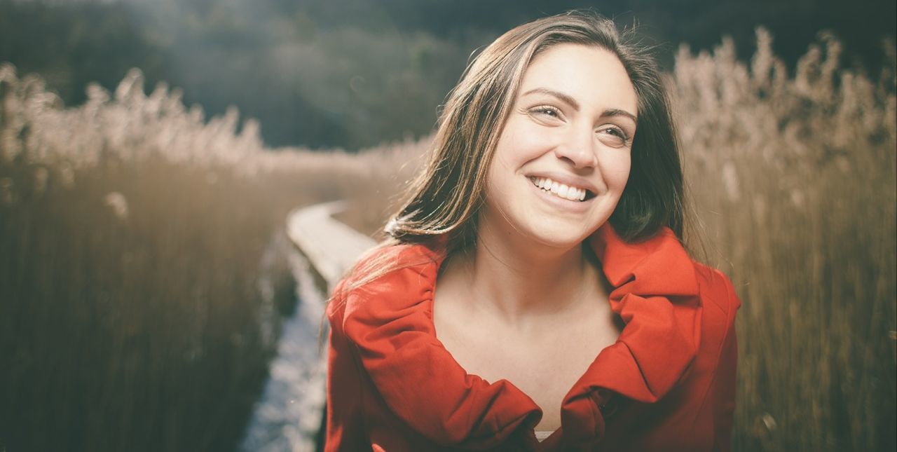 focus on foreground, lifestyles, person, leisure activity, front view, portrait, casual clothing, looking at camera, smiling, young adult, red, holding, waist up, headshot, standing, happiness, outdoors, day