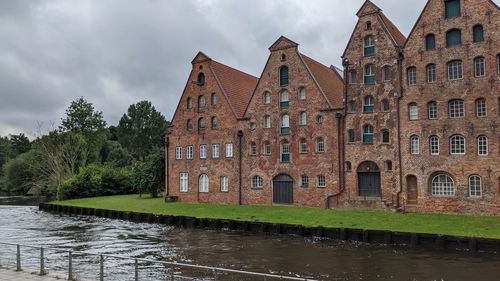 Buildings by river against sky