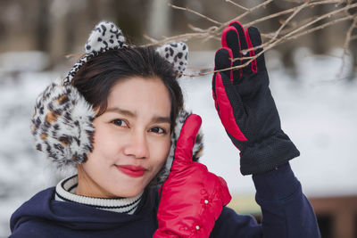 Portrait of woman pointing at dried plant during winter