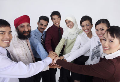 Portrait of colleagues with stacking hands against white background