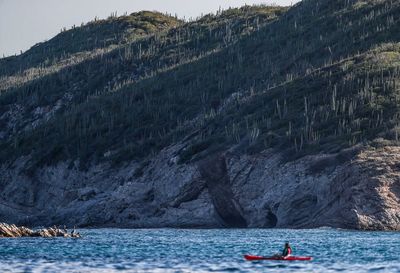 People on boat against mountain